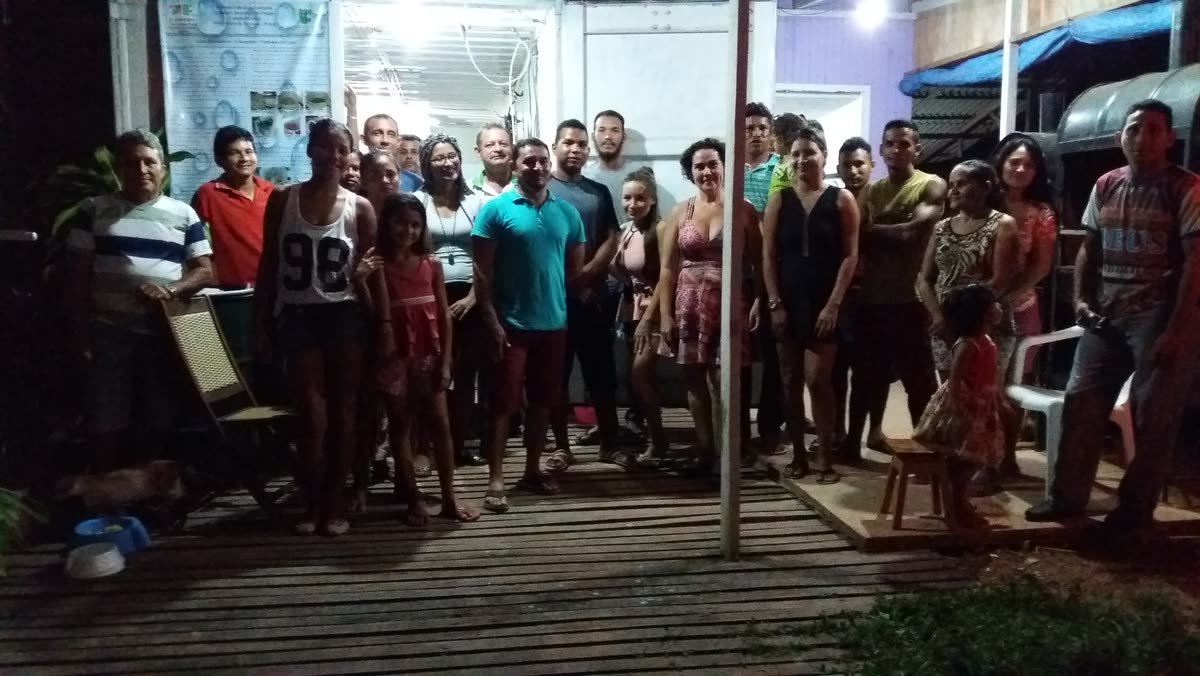 Moradores reunidos à noite em frente a uma casa da comunidade