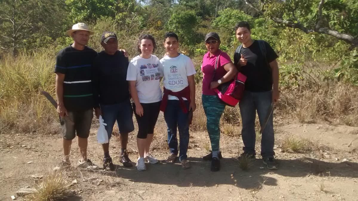 Grupo de jovens e moradores em uma trilha em área de vegetação