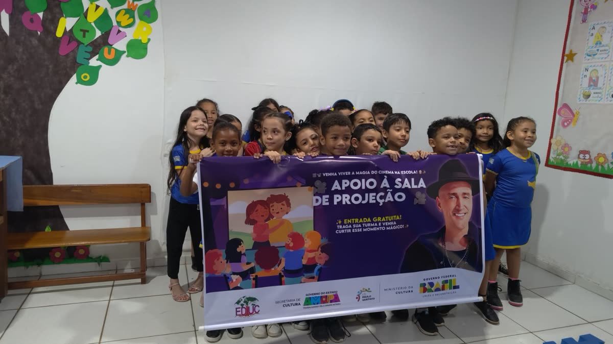 Crianças de uniforme escolar assistem a um filme projetado na parede