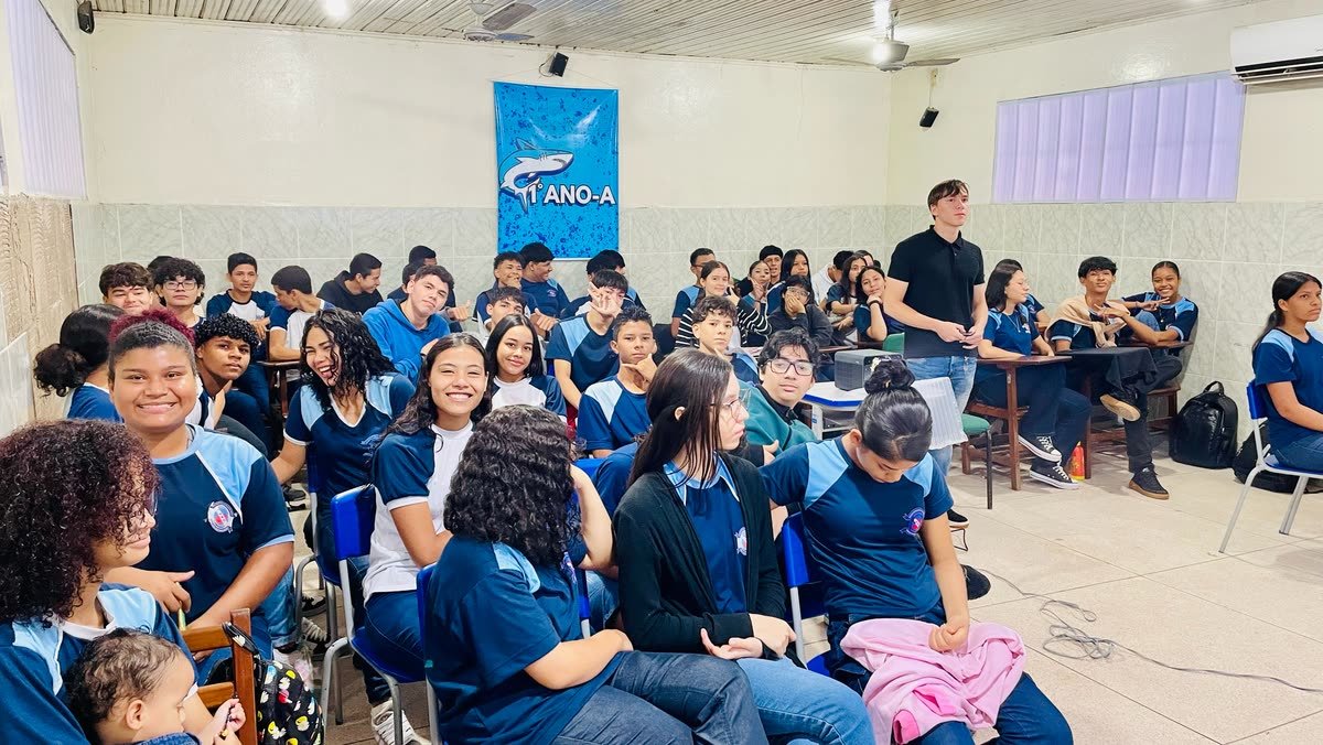 Estudantes do ensino médio sentados em uma sala de aula, ao lado de um projetor