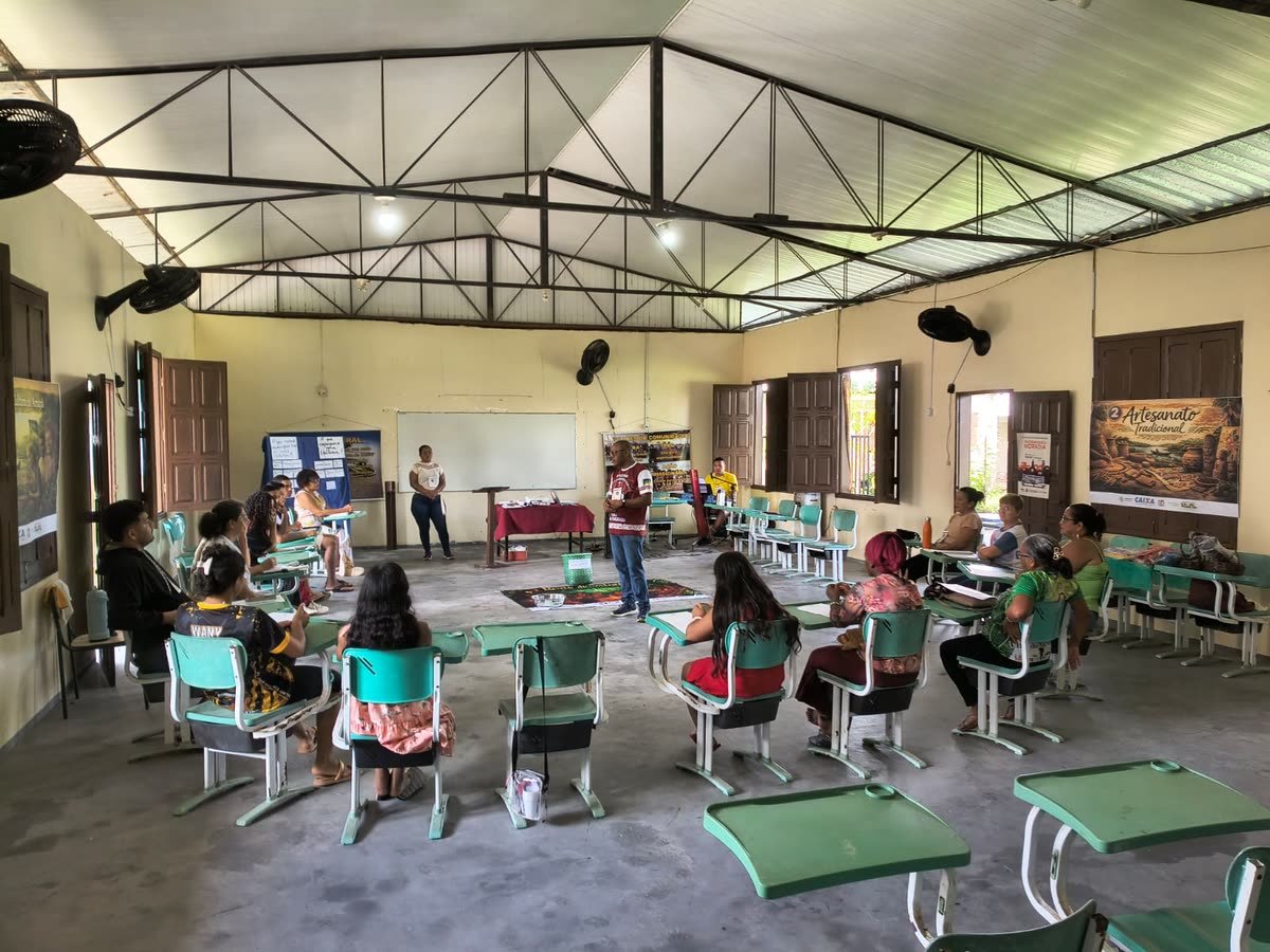 Participantes sentados em roda em um salão, com cartazes de artesanato tradicional nas paredes