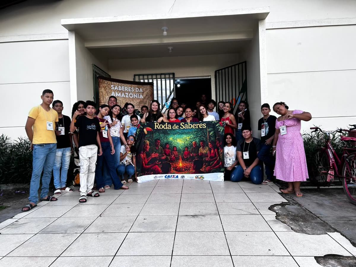 Participantes reunidos em frente a um prédio segurando a faixa Roda de Saberes